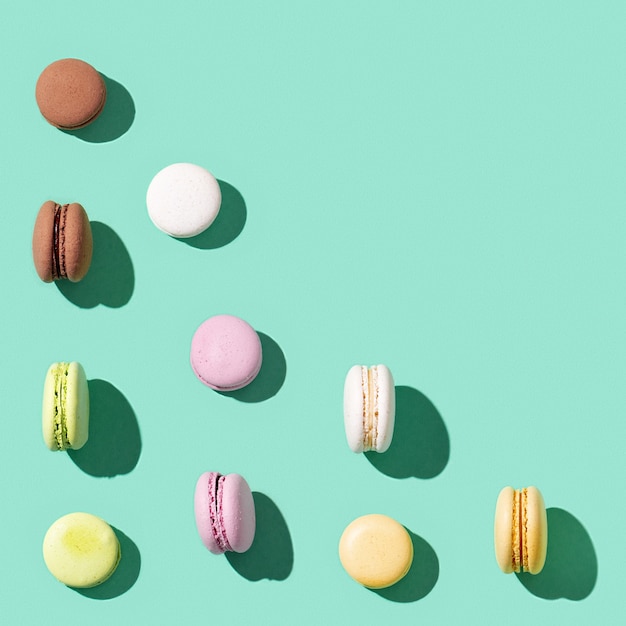 Patroon van verschillende cake bitterkoekjes op heldere blauwgroene kleur achtergrond, multi gekleurde Franse biscuit macarons. Zoet smakelijk vakantievoedsel.