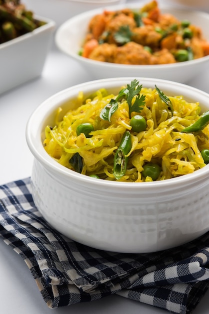 Patta gobi sabji o cavolo sabzi con piselli verdi e foglie di curry, servito in una ciotola su sfondo lunatico, messa a fuoco selettiva