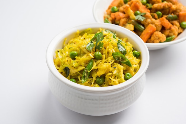 Patta Gobi Sabji OR Cabbage sabzi with green peas and curry leaves, served in a bowl over moody background, selective focus