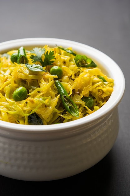 Patta Gobi Sabji OR Cabbage sabzi with green peas and curry leaves, served in a bowl over moody background, selective focus