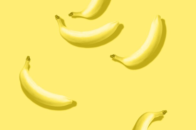 Modello di banane con ombra prominente su sfondo giallo pastello tonica colore illuminante