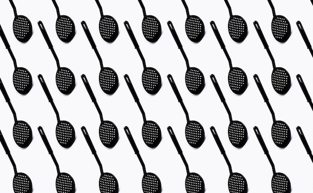 Pattern of black plastic skimmer spoon on white background