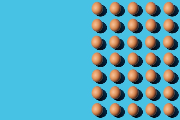 A pattern of brown chicken eggs on the right half of the blue\
background left side for copy space