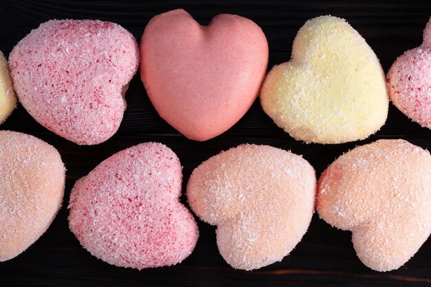 Pattern of cakes in the shape of heart on wooden background. Top view.