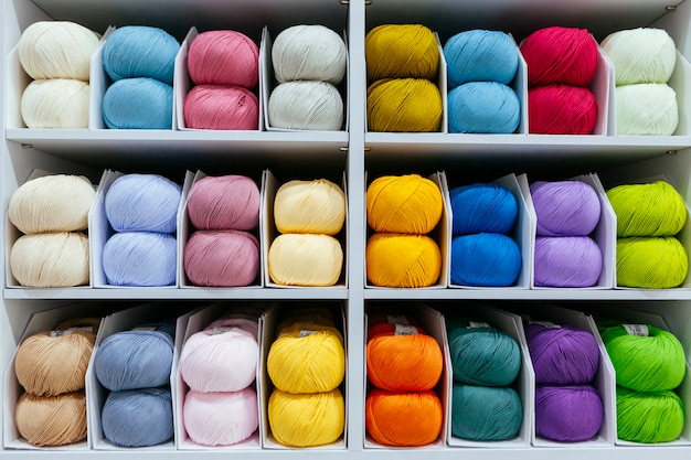 Pattern of colorful different wools yarns organized by color on\
a retail shop