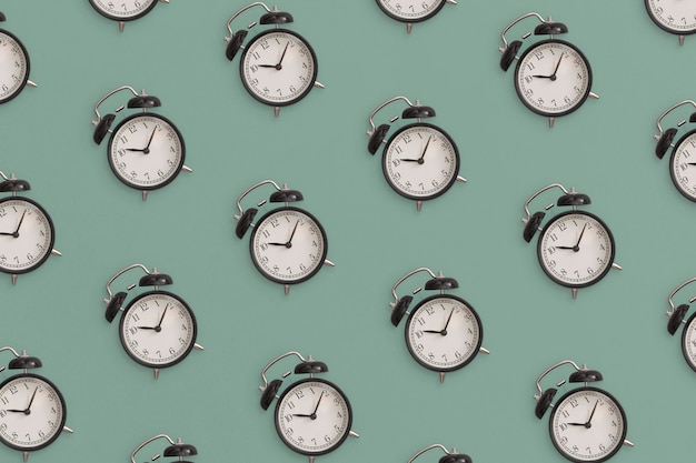 Photo pattern composition of  black antique alarm clock on green background