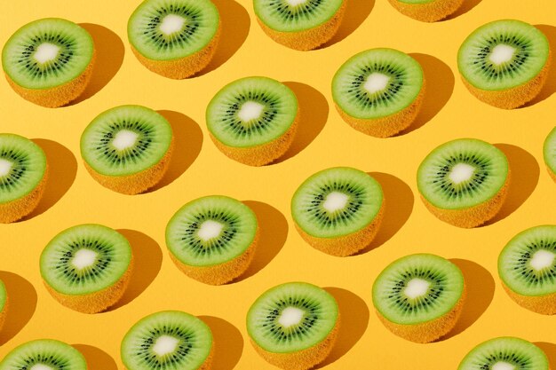 Pattern from halves of ripe juicy kiwi fruit on a yellow background