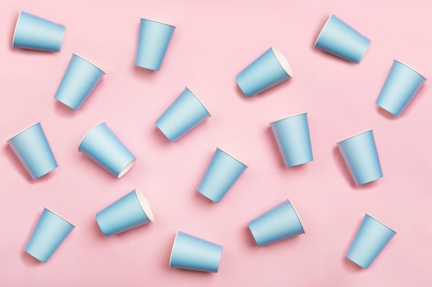 분홍색 배경에 무작위로 배열된 민트 블루 종이 마시는 컵의 패턴