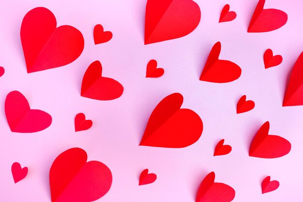 Modello da cuori di carta rossa su sfondo rosa. il giorno di san valentino concetto. disposizione piatta.