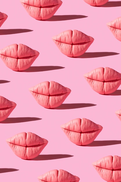 Pattern from pink lips on pink background Creative beauty concept vertical background