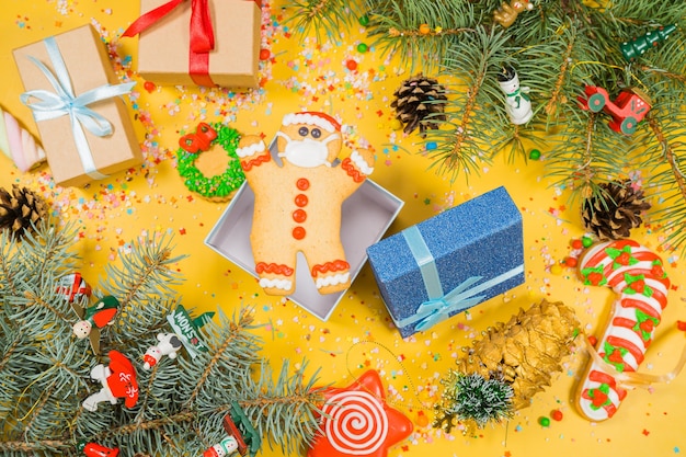 Pattern of gingerbread cookies in different shapes on yellow surface flat lay top view