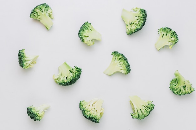 Photo pattern of halved cut broccoli pieces on white backdrop