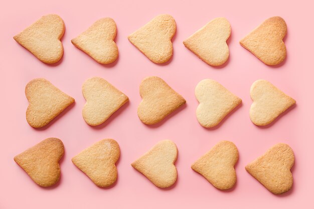 Pattern of homemade traditional heart shaped cookies for Valentine's day on pink