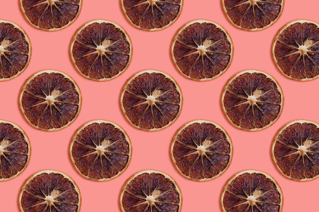 Pattern made of dried orange slices on a coral background