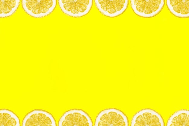 Photo pattern made from fresh lemon slices on a yellow background with copy space in the middle