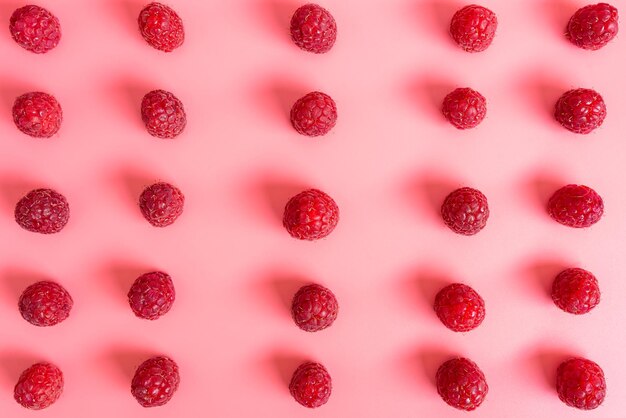 Pattern made from fresh raspberries top view flat lay pattern isolated on a light pink background