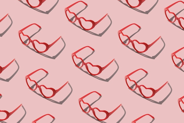 Pattern made with red heart shaped sunglasses on pastel color background Valentine day concept