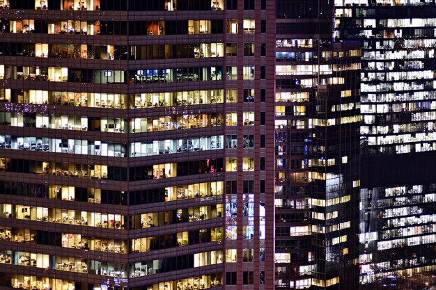 Pattern of office buildings windows illuminated at night Glass architecture corporate building