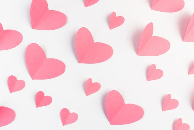 A pattern of paper pink hearts on a white background. The concept of Valentine's Day.