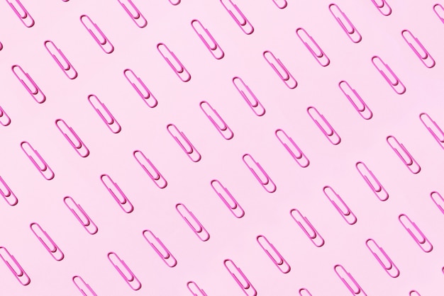 Pattern of pink paper clips on pastel background