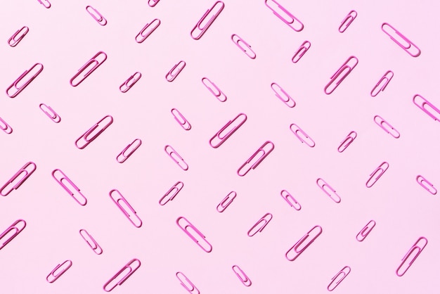 Pattern of pink paper clips on pastel background