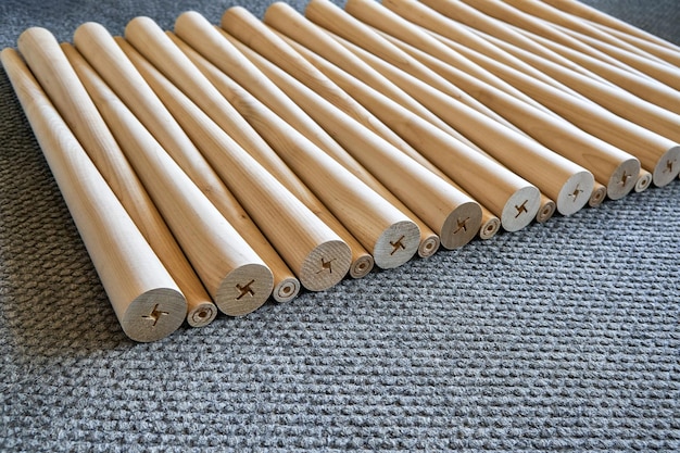 Pattern of polished conical wooden table legs on the gray carpet closeup view