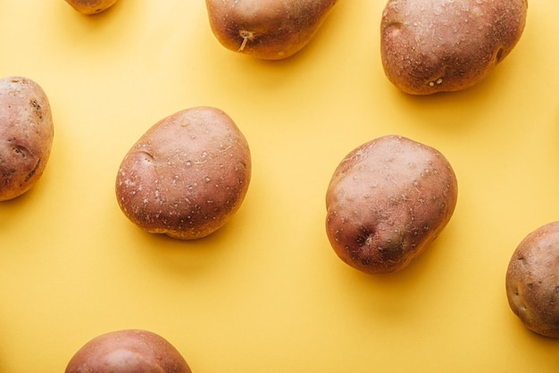 Узор из сырого цельного свежего картофеля на желтом фоне