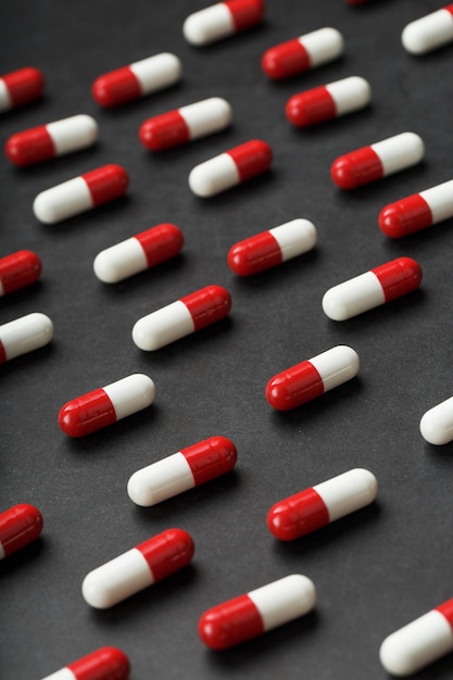 A pattern of red and white pill capsules on a black background background.