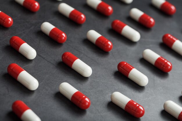 A pattern of red and white pill capsules on a black background background.