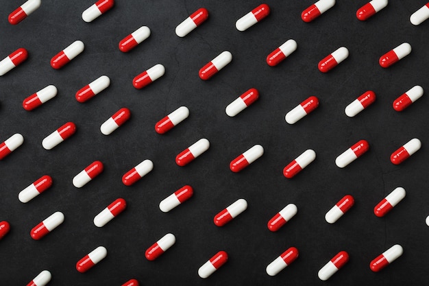 A pattern of red and white pills of medical pills on a black background