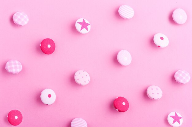 Photo pattern of textile buttons on pink background