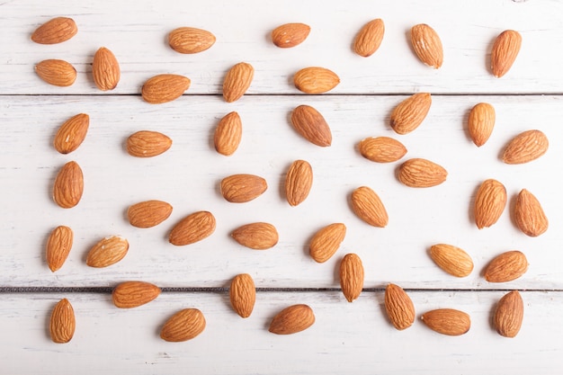 Pattern and texture made from almonds on white wooden background, flat lay.