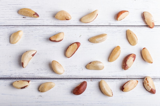 Pattern and texture made from Brazil nuts on white wooden background, flat lay.