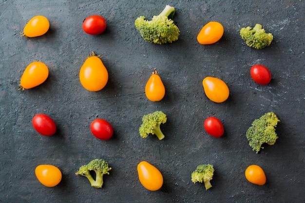 Pattern of tomato mini and broccoli cabbage on a dark surface