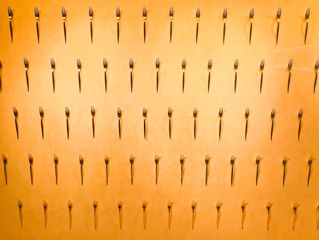 The pattern of a variety of metal forks cutlery on the wall on a yellow background Texture