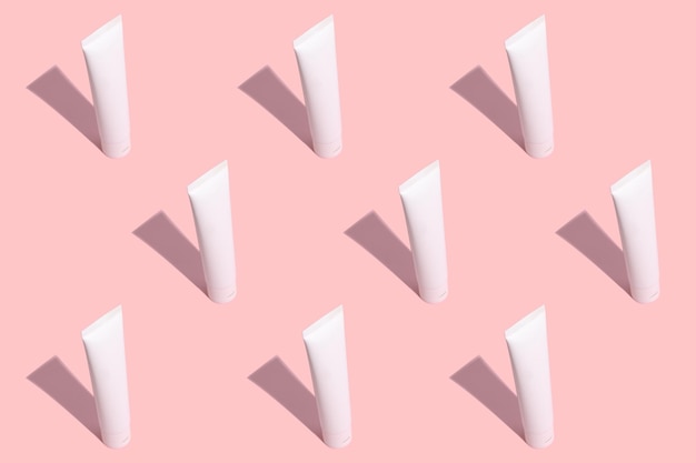 Pattern white tube of cosmetic cream with a hard black shadow
on a pink background