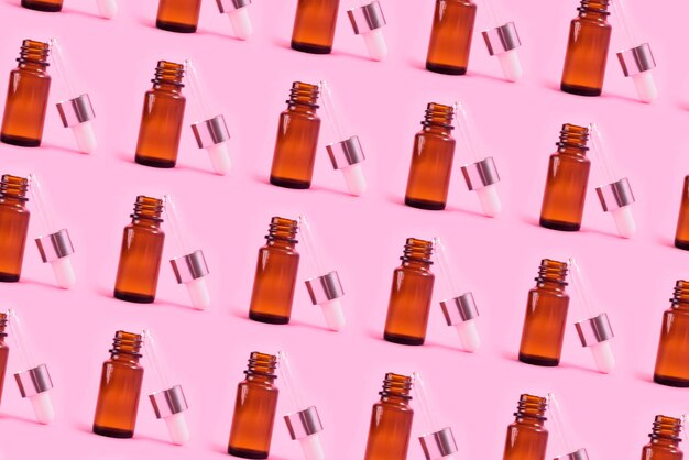 Pattern with glass dropper bottle on the pink background