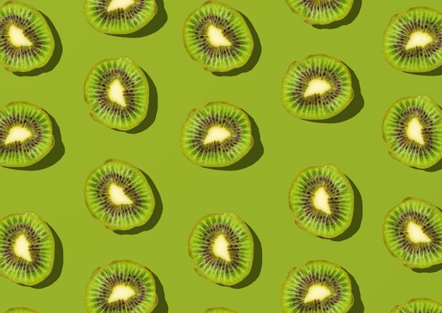 Photo pattern with kiwi slice on green top view flat lay.