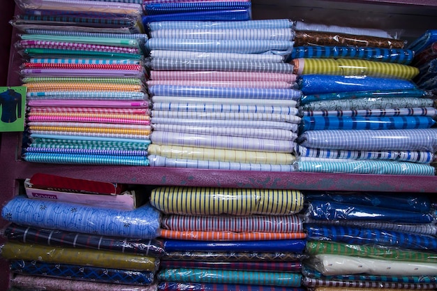 Узорчатые текстильные ткани, сложенные на полке розничного магазина для продажи