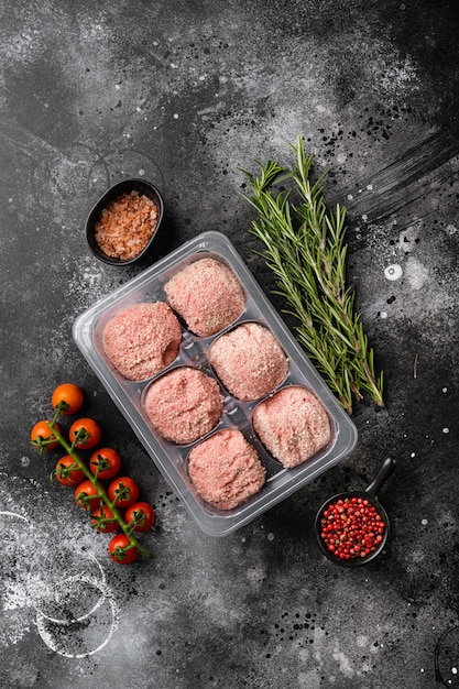 Photo the patties of minced meat on a tray set, on black dark stone table background, top view flat lay