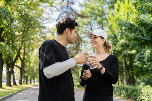 Pauze drinken gebotteld water man en vrouw trainen in het park Een jong stel gelukkig