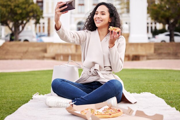 Pauzetijd is pizzatijd Shot van een aantrekkelijke jonge vrouwelijke universiteitsstudent die tijdens haar pauze selfies buiten op de campus neemt