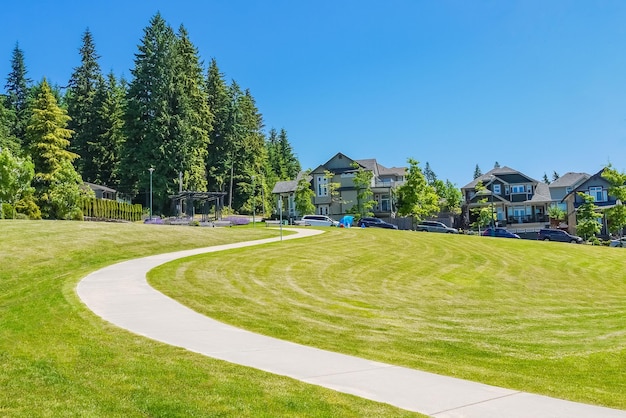 Paved pathway over green lawn on the slope in front of new townhouses