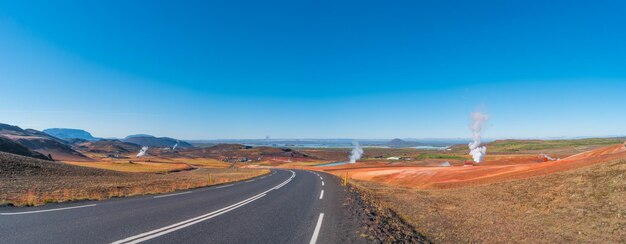 Photo paved ring road going through volcanically active zone hverir near myvatn lake in highlands of iceland resembling martian red planet landscape at summer and blue sky