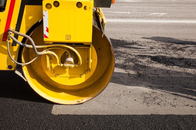 Pavement machine laying fresh asphalt or bitumen on top of the gravel base during highway construction