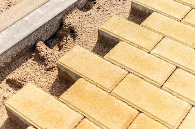 Pavement repair and laying of paving slabs on the walkway, stacked tile cubes on the background. Laying paving slabs in the pedestrian zone of the city, sand filling. Road tiles and curbs.