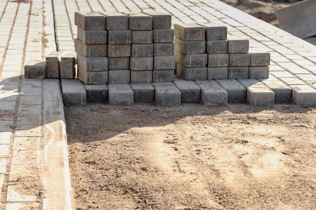 Pavement repairs and paving slabs laying on the prepared surface with tile cubes in the background Laying paving slabs in the pedestrian zone of the city Paving slabs and curbs