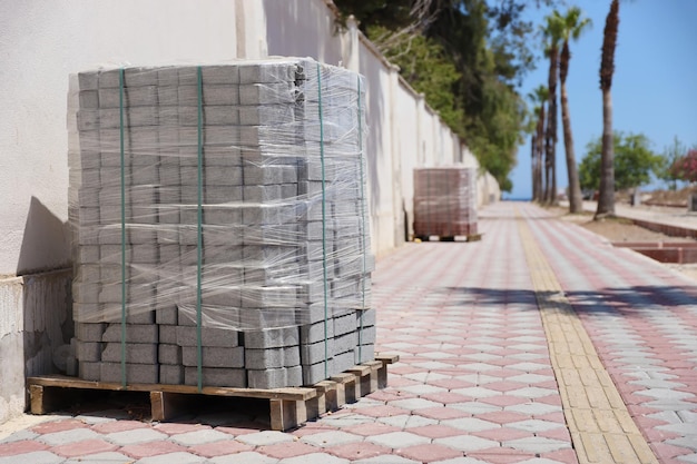 Pietre per lastricati su pallet di legno sul marciapiede della strada