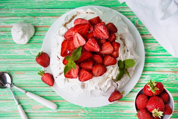 Pavlov's cake met aardbeien en room op een rustieke achtergrond, bovenaanzicht