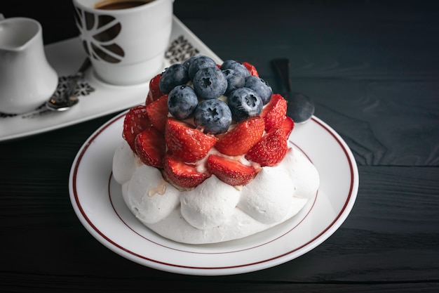 Pavlova dessert on a dark wooden table